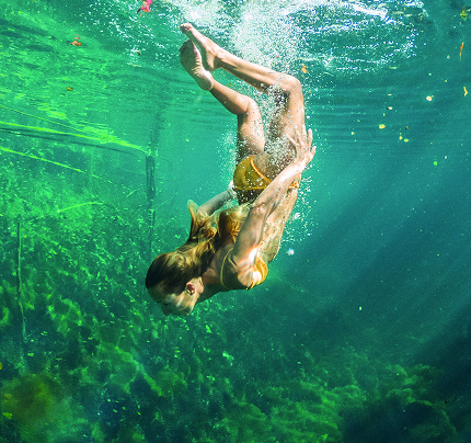 Pessoa mergulhando em piscina natural de águas verdes